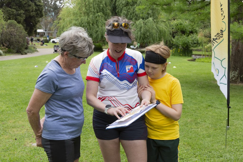 Three orienteers looking at a map in a park setting