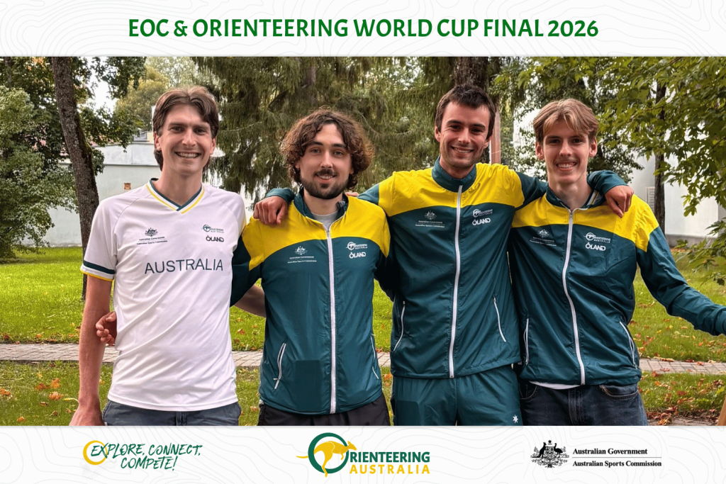 Four young men in team jerseys stand with arms around each other, smiling in a park; one wears a white Australia shirt, the others teal/yellow jackets, event logos visible at bottom.